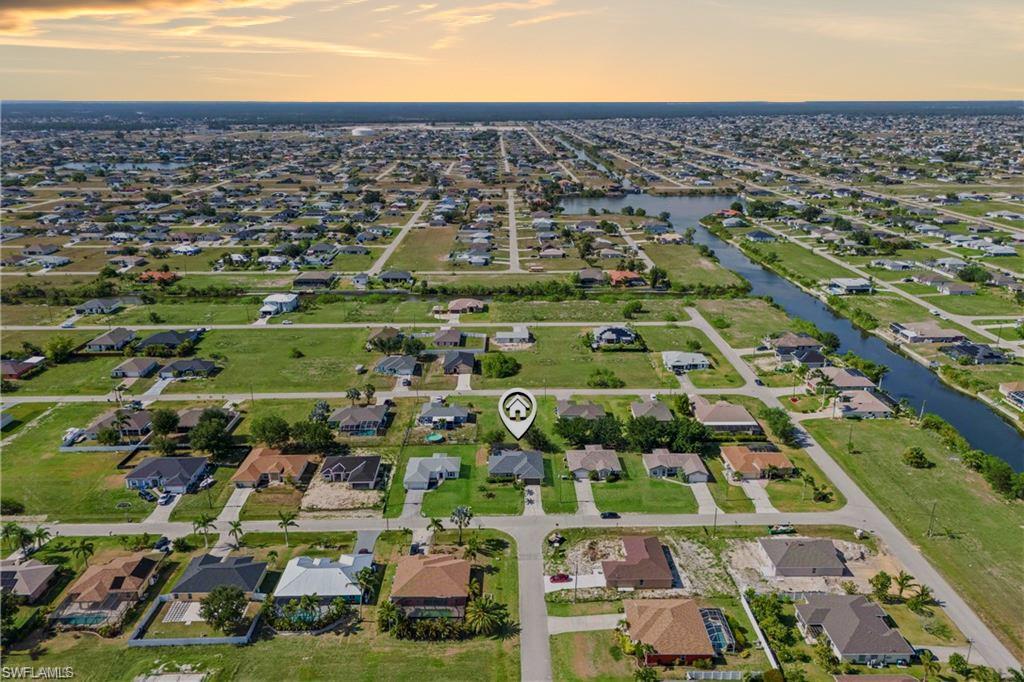 The aerial view showcases the home in a peaceful, well-landscaped community, with spacious properties. In the distance, a serene water view adds a tranquil backdrop.