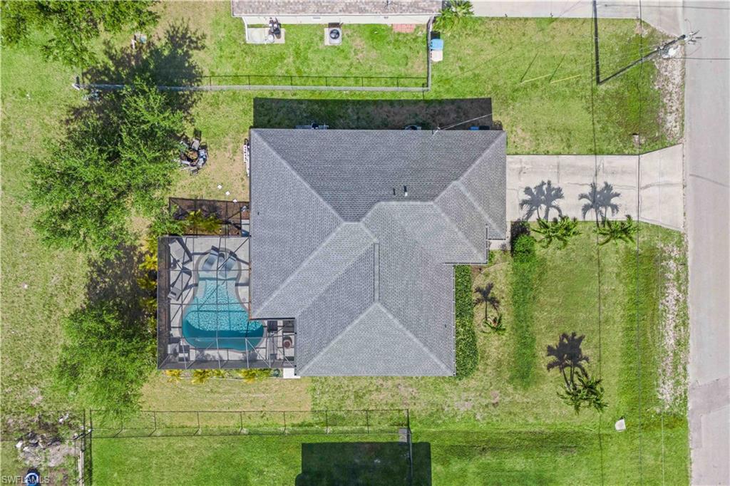 An aerial view reveals a stunning home with lush landscaping, a sparkling pool, separate spa, and spacious outdoor patio, offering a perfect blend of luxury and privacy.