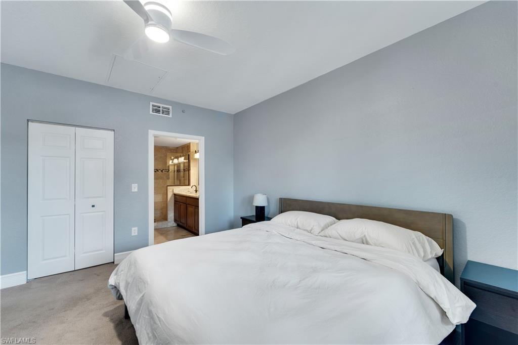 Bedroom with light carpet, a closet, ensuite bathroom, and ceiling fan