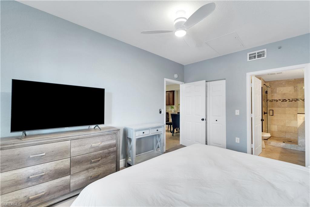 Bedroom with ceiling fan, ensuite bath, and attic access