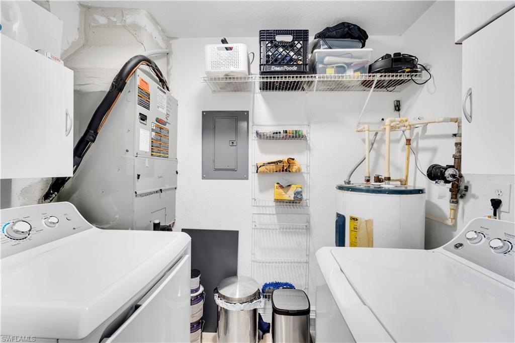 Washroom featuring washer / dryer, electric panel, water heater, and heating unit