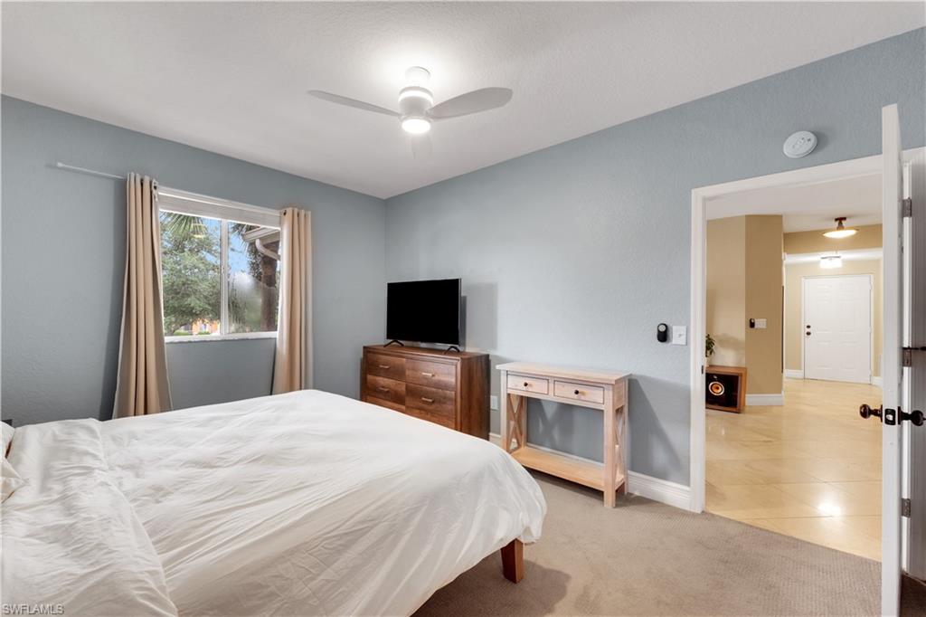 Bedroom featuring light carpet, light tile patterned floors, and ceiling fan