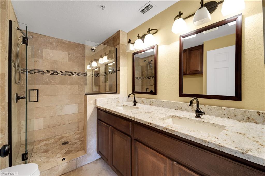 Bathroom featuring double vanity, a stall shower, and light tile patterned floors