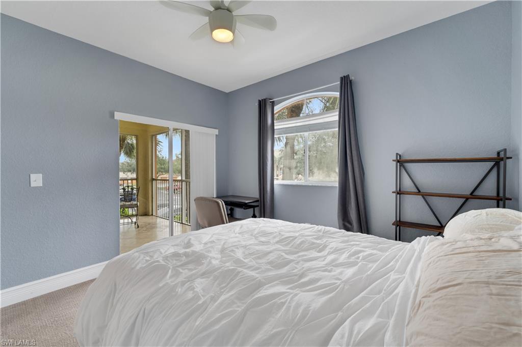 Bedroom with access to exterior, a textured wall, ceiling fan, and light colored carpet