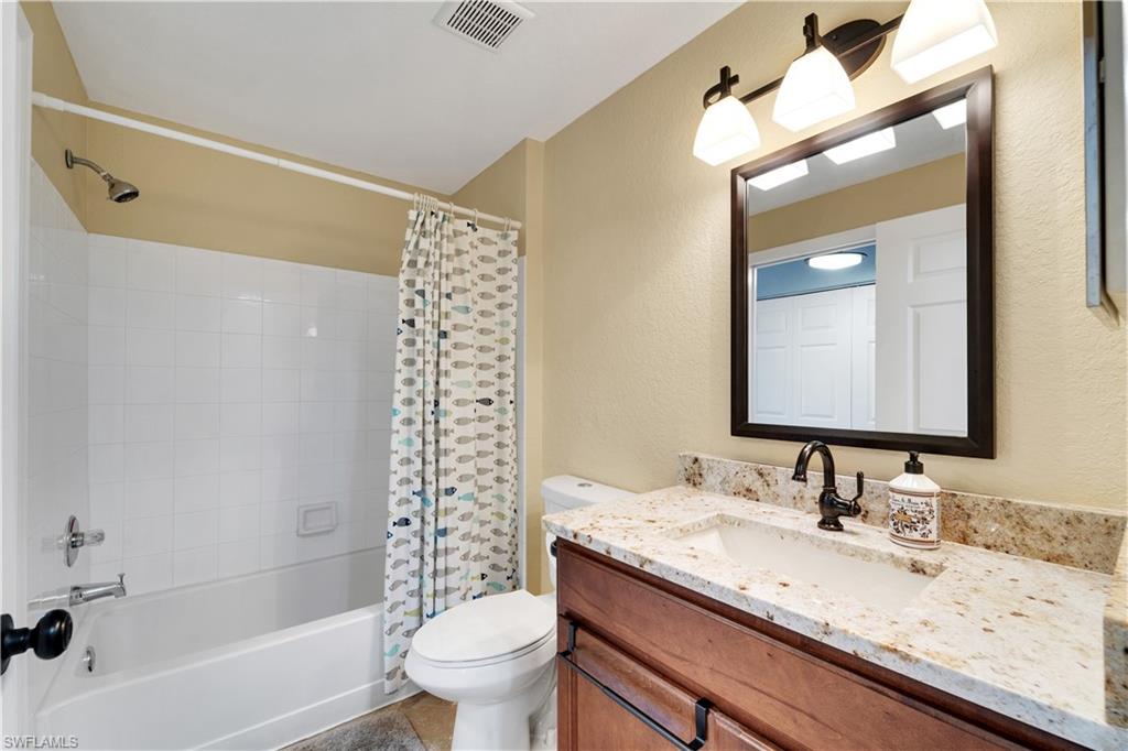 Bathroom with shower / tub combo, vanity, and a textured wall