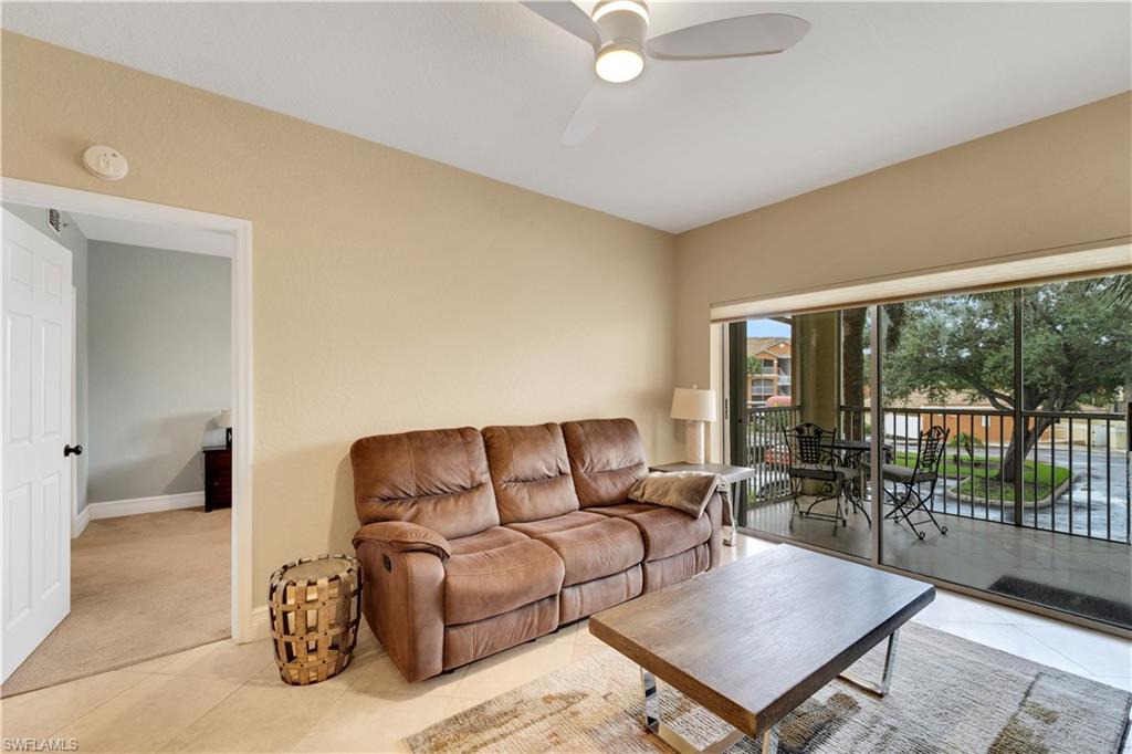 Carpeted living area with tile patterned floors and a ceiling fan