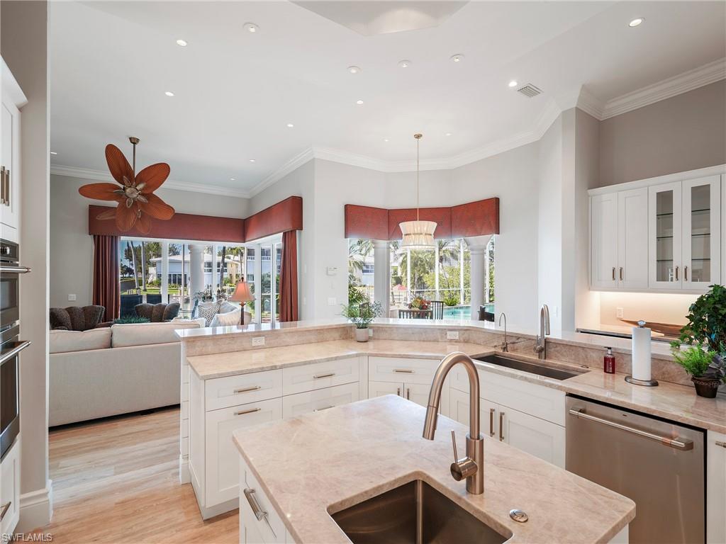 Kitchen with white cabinetry, glass insert cabinets, stainless steel appliances, open floor plan, and pendant lighting