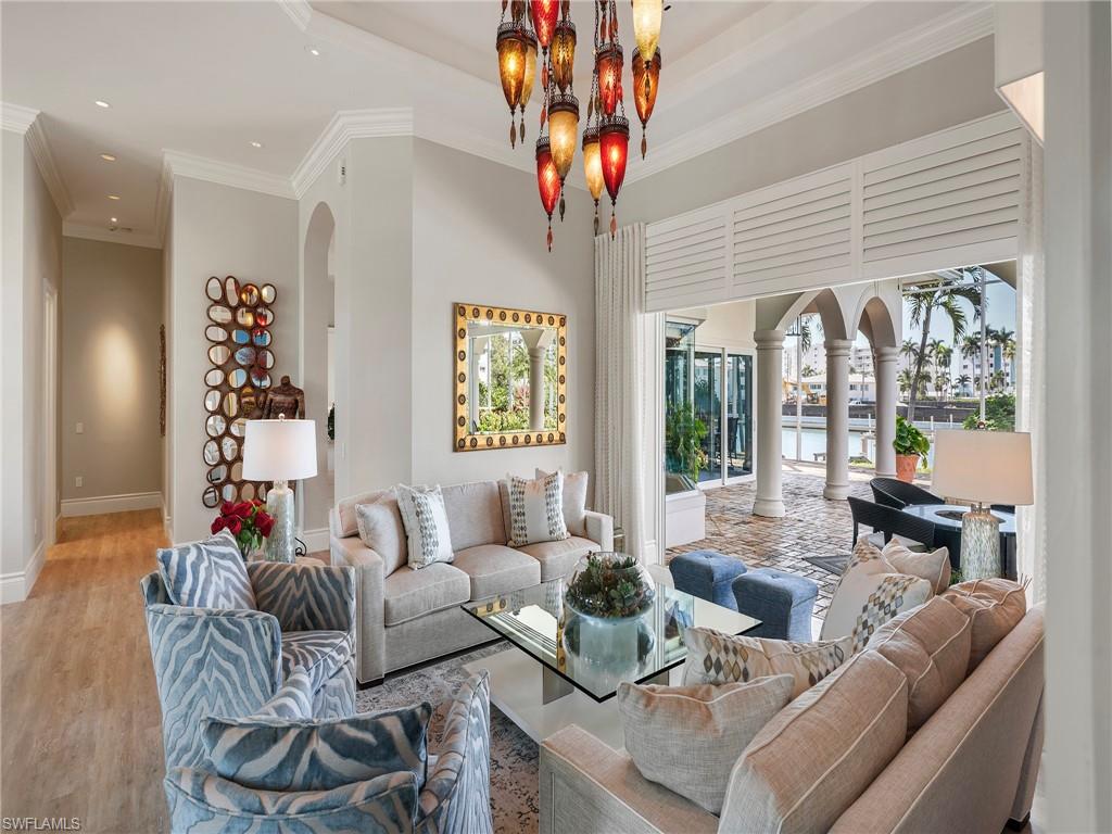 Living area with arched walkways, ornamental molding, wood finished floors, a chandelier, and a water view