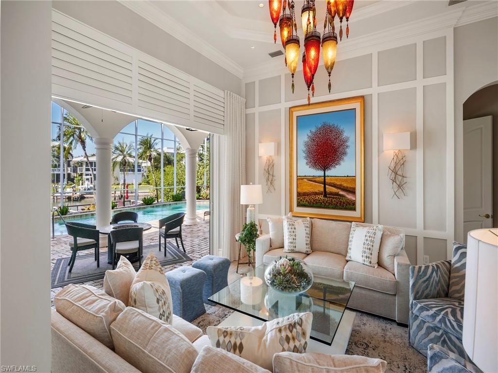 Living area with a decorative wall, crown molding, and arched walkways