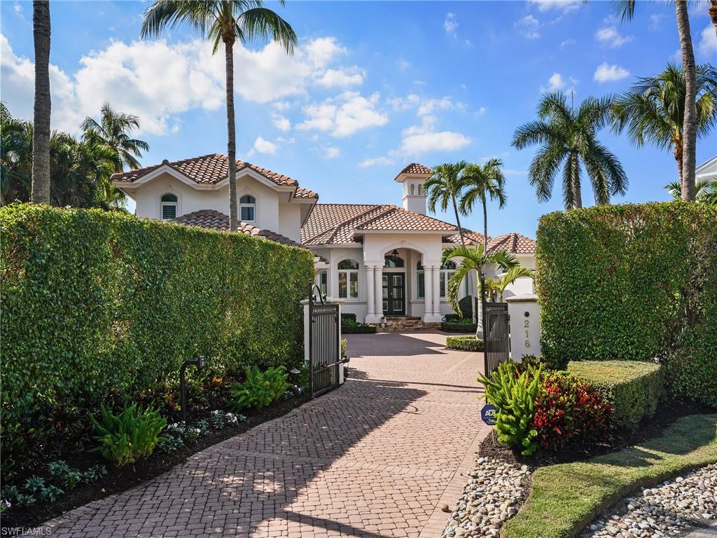 Mediterranean / spanish house with decorative driveway, stucco siding, a gate, and a tile roof