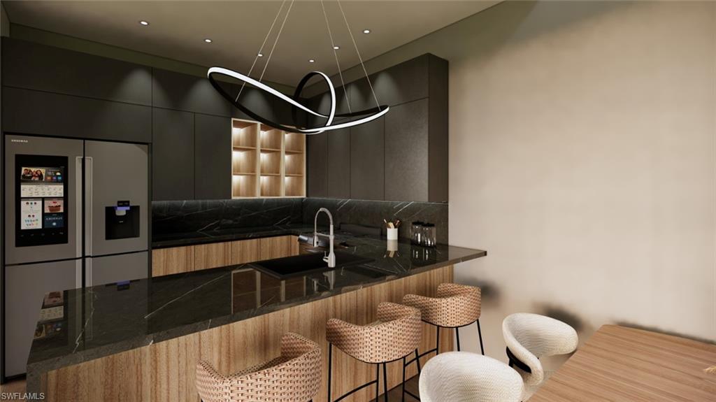 Kitchen with a kitchen bar, stainless steel fridge, dark stone counters, modern cabinets, and a peninsula