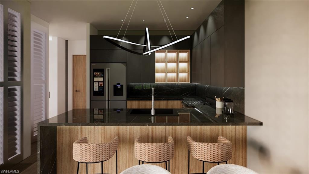 Kitchen featuring modern cabinets, stainless steel fridge, a kitchen bar, a peninsula, and dark stone countertops