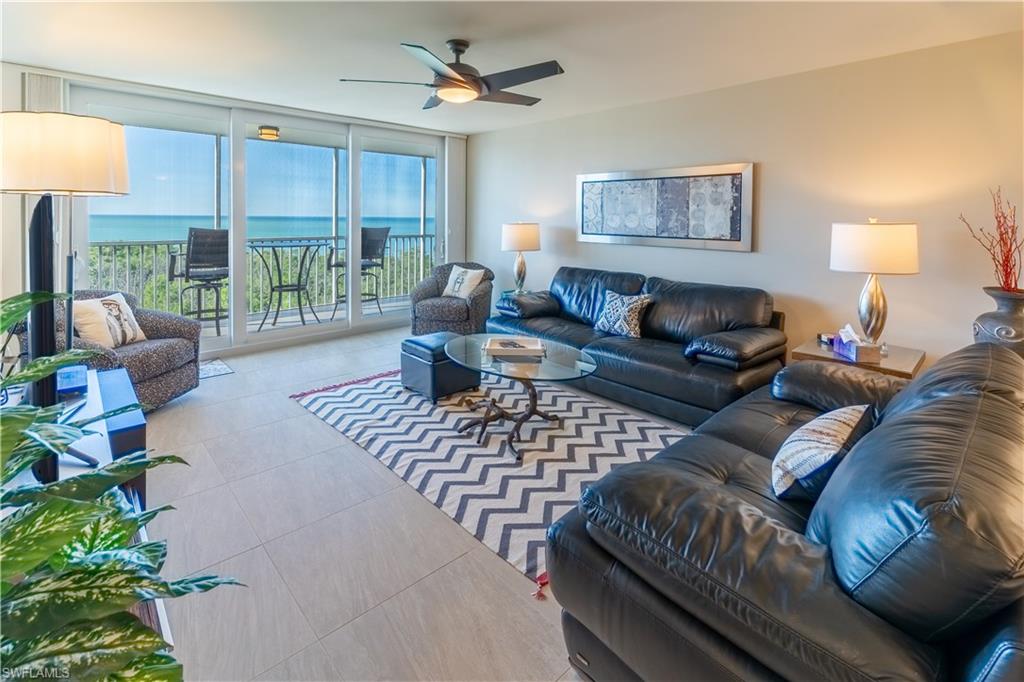 Tiled living area featuring floor to ceiling windows, a ceiling fan, and a water view