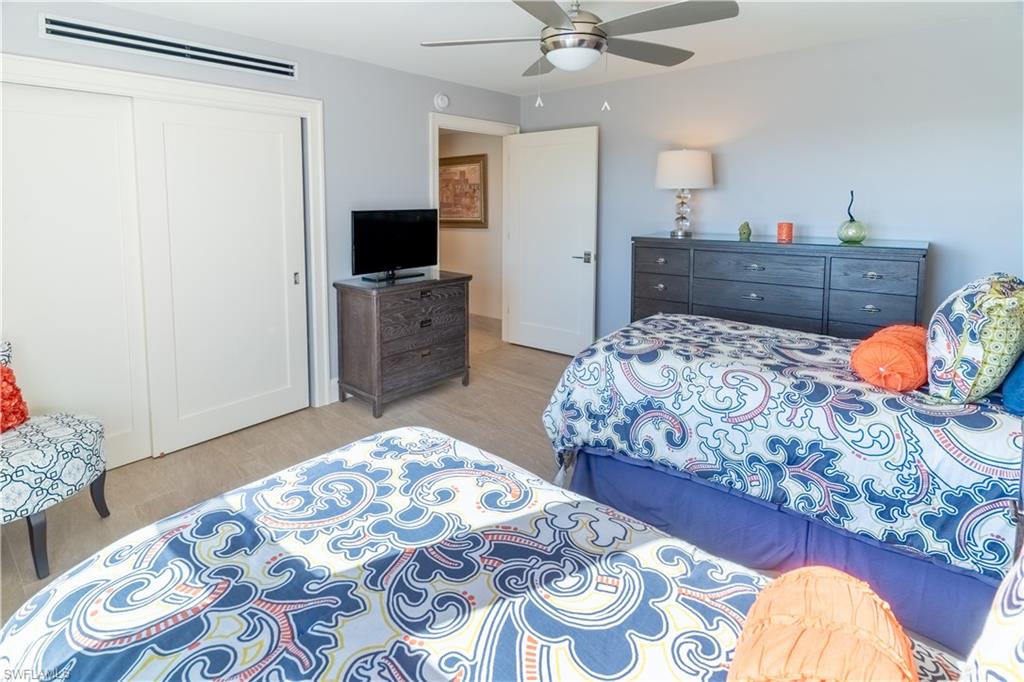 Bedroom with a wall mounted air conditioner, a closet, ceiling fan, and light wood-type flooring