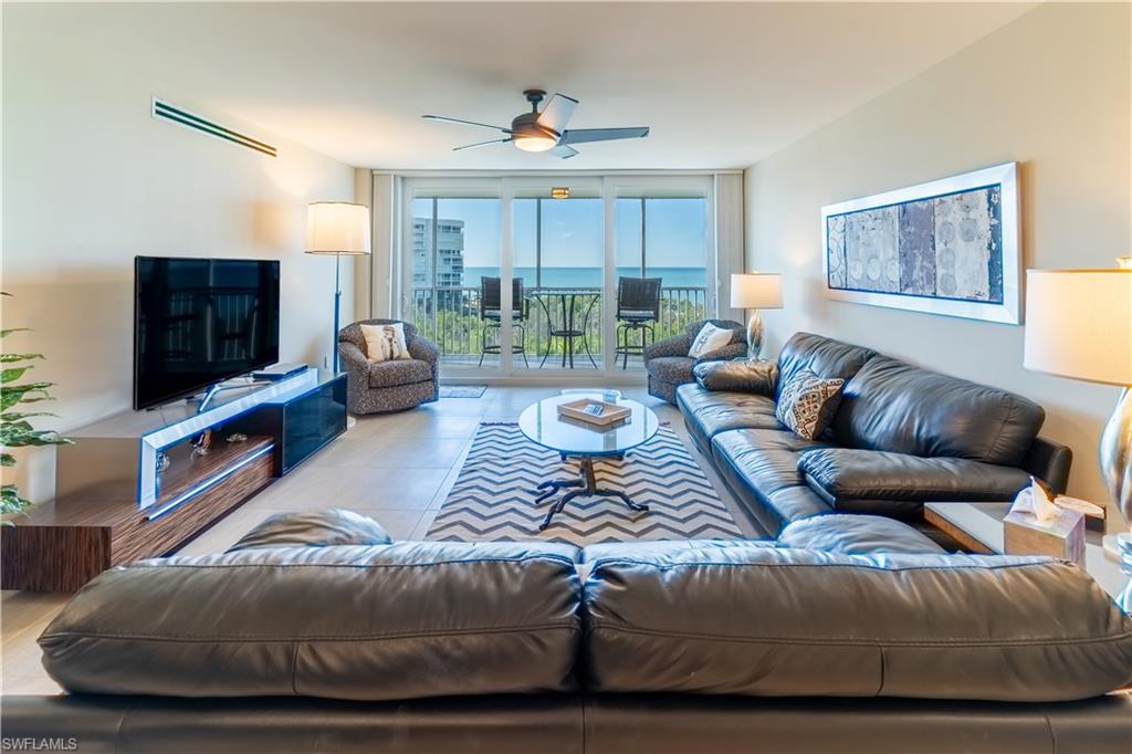 Living area with a wall of windows, ceiling fan, and tile patterned flooring