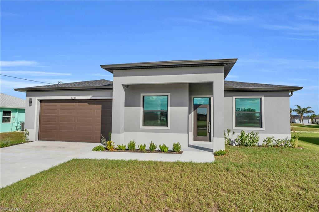 Prairie-style house featuring a front lawn, stucco siding, concrete driveway, and a garage