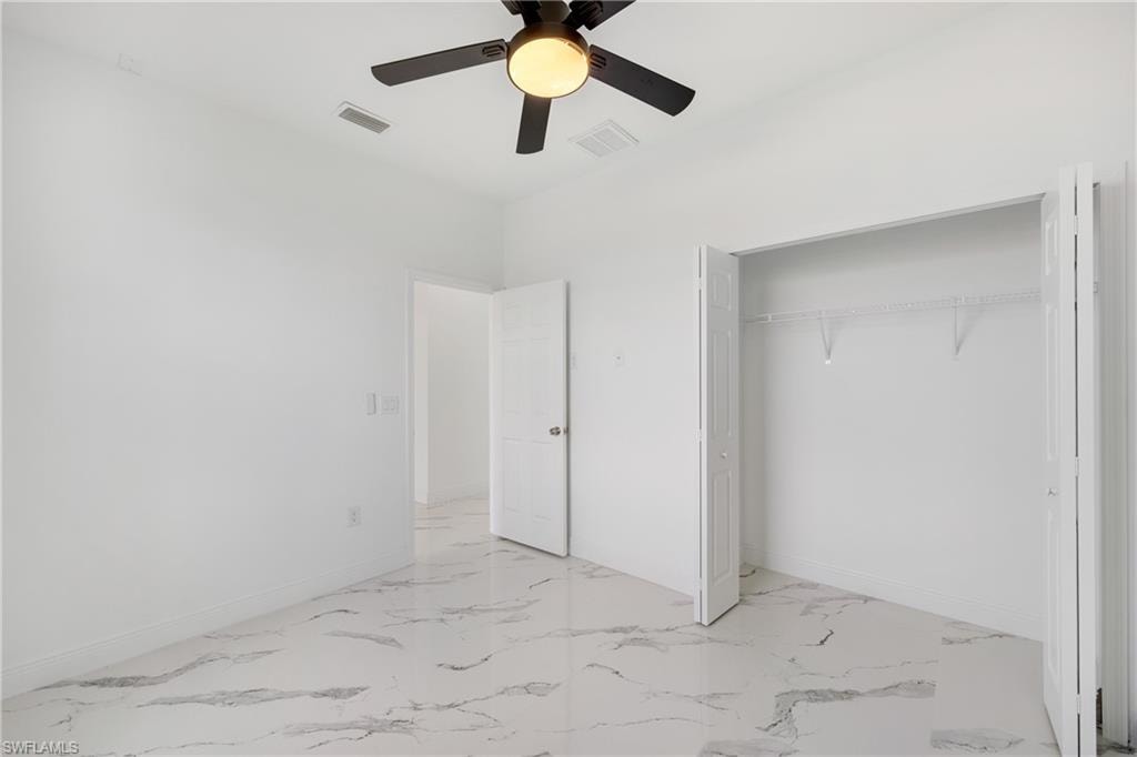 Unfurnished bedroom featuring light marble finish flooring, ceiling fan, and a closet