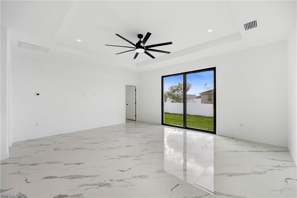 Unfurnished room featuring light marble finish flooring, recessed lighting, a raised ceiling, and a ceiling fan