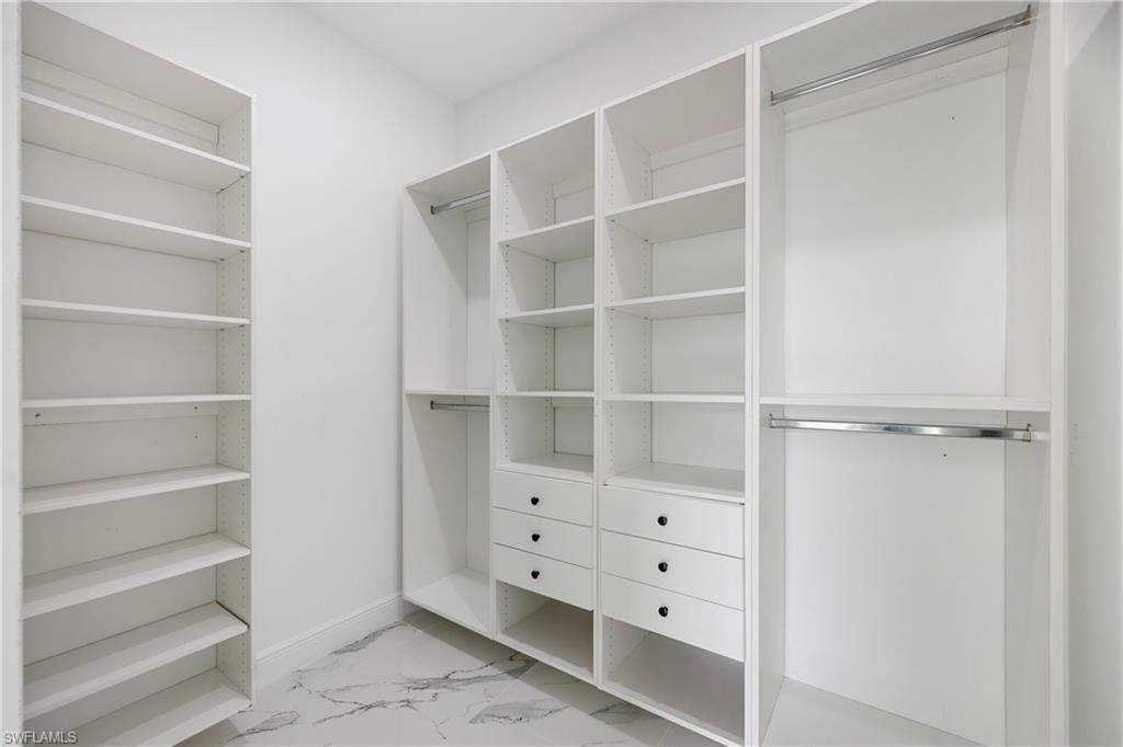 Spacious closet featuring light marble finish floors