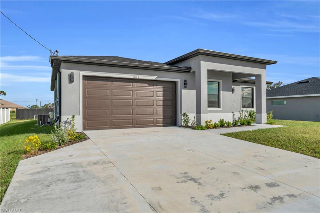 View of front facade with a front lawn, stucco siding, and driveway