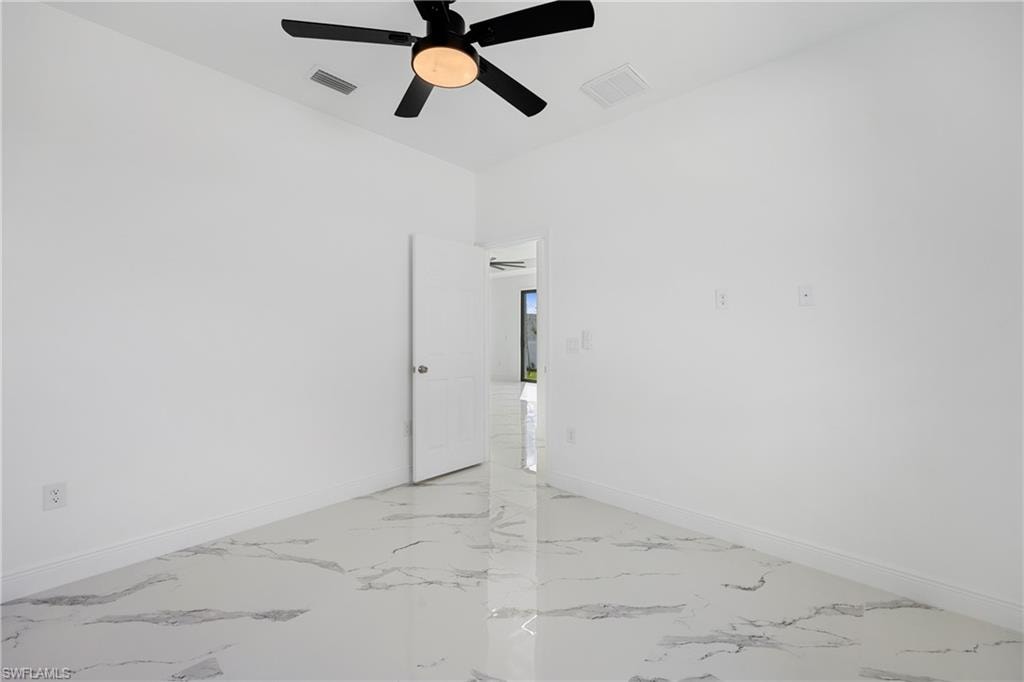 Empty room with light marble finish floors and a ceiling fan