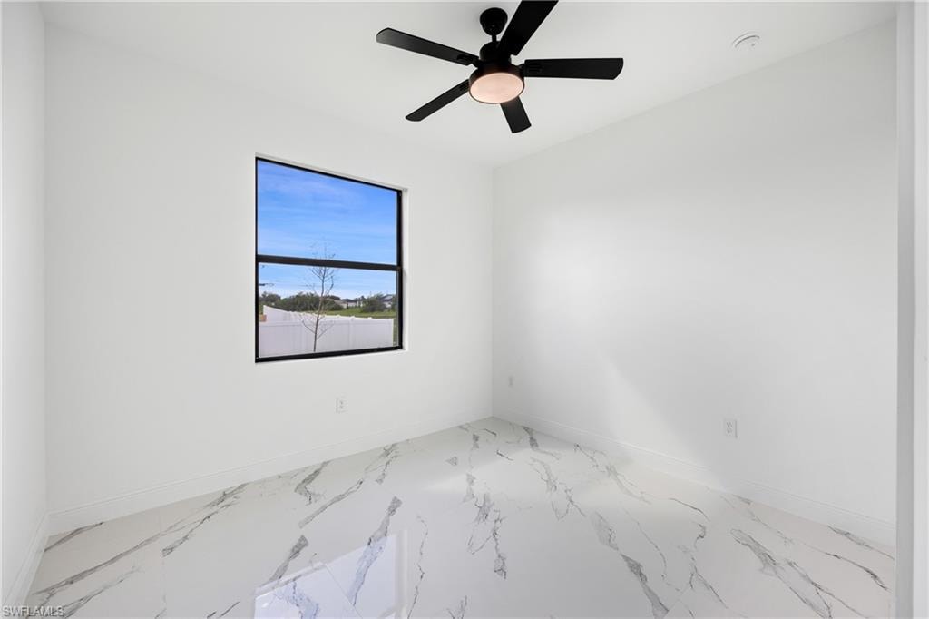 Unfurnished room featuring marble finish floors and ceiling fan