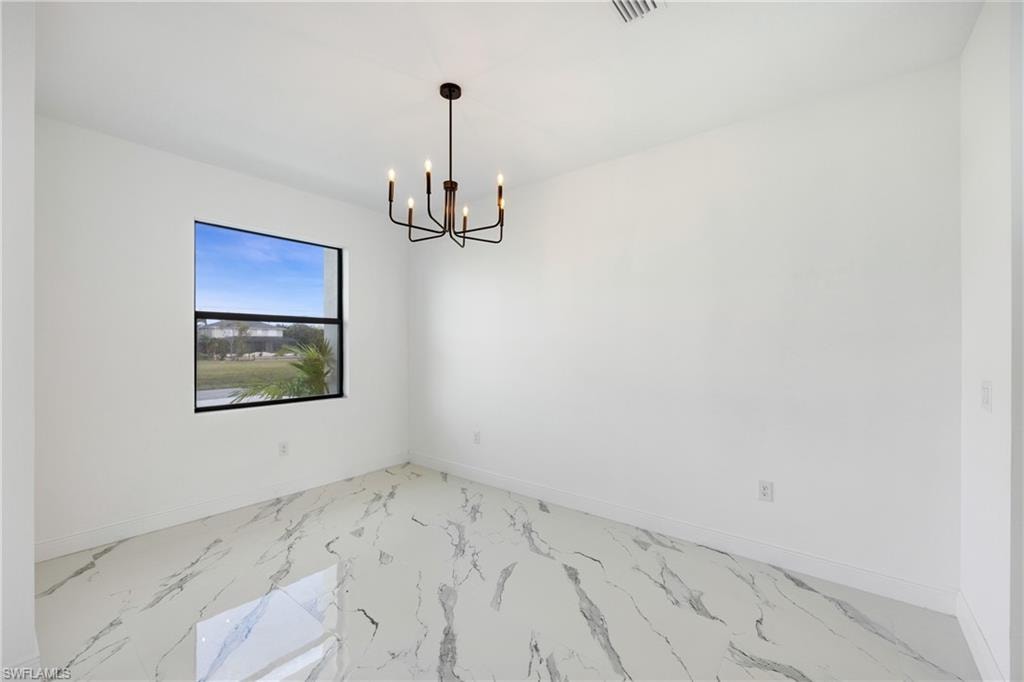 Unfurnished room with marble finish floors and a chandelier