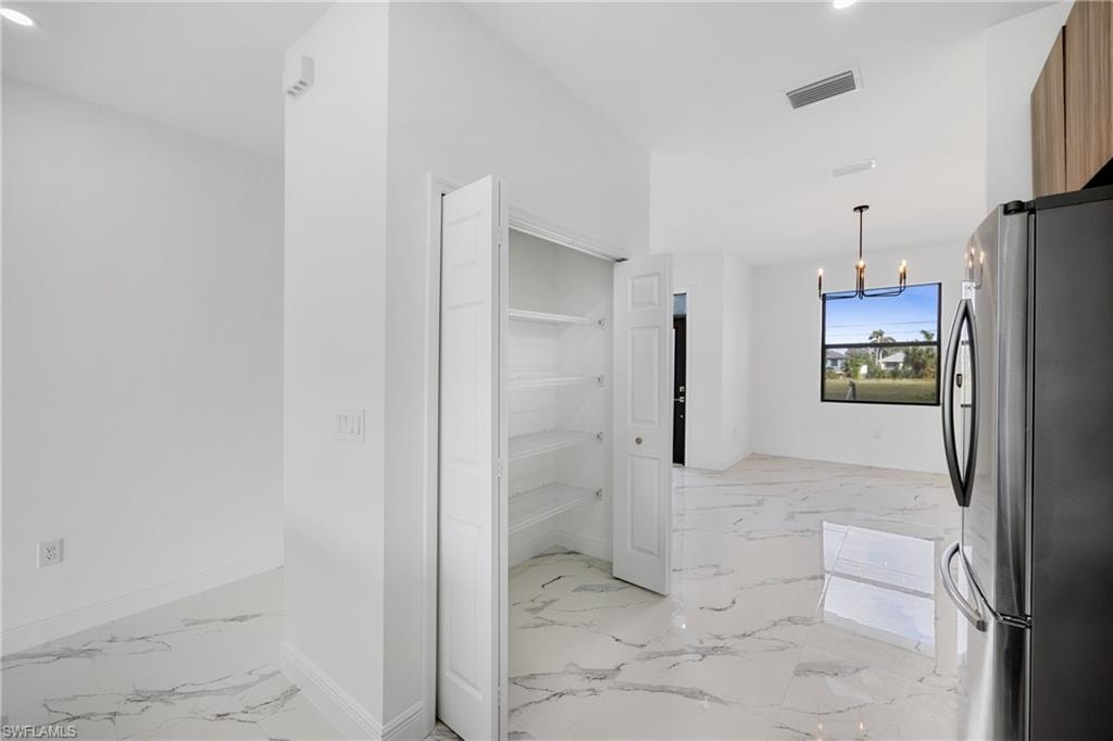 Corridor featuring a chandelier, light marble finish floors, and recessed lighting