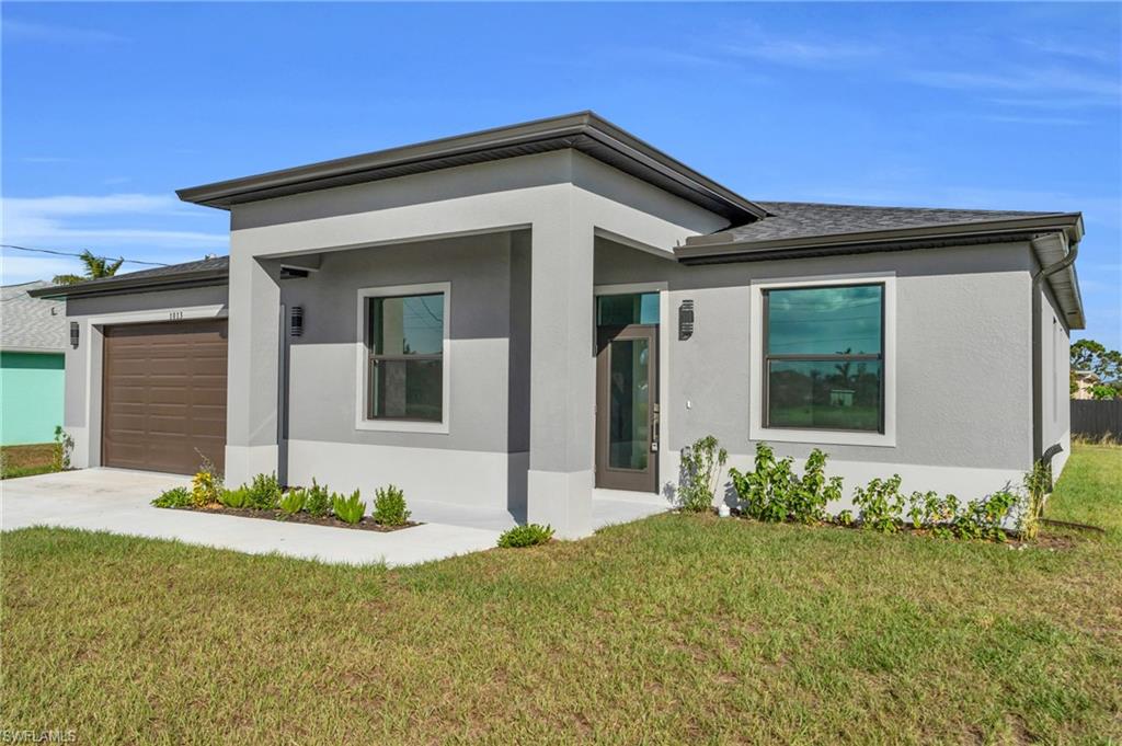 View of front facade featuring stucco siding, a front lawn, an attached garage, and covered porch