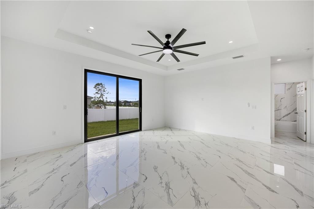 Spare room with light marble finish flooring, a tray ceiling, recessed lighting, and a ceiling fan
