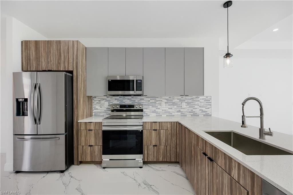 Kitchen with appliances with stainless steel finishes, light marble finish floors, light stone counters, and modern cabinets