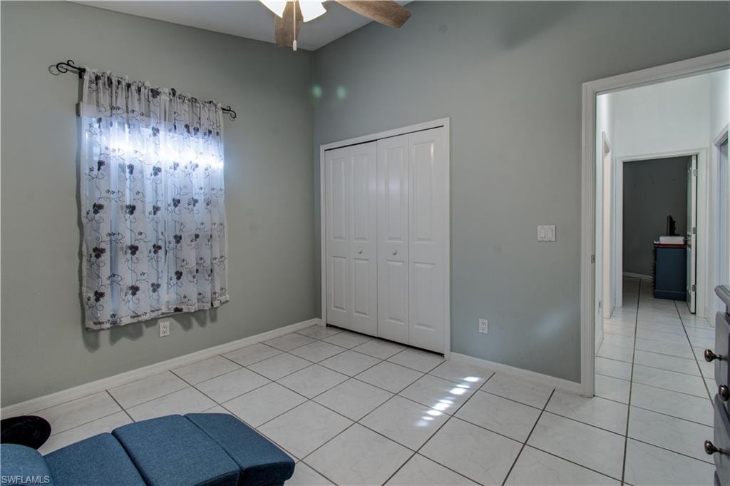 Unfurnished bedroom with a closet, light tile patterned floors, and a ceiling fan