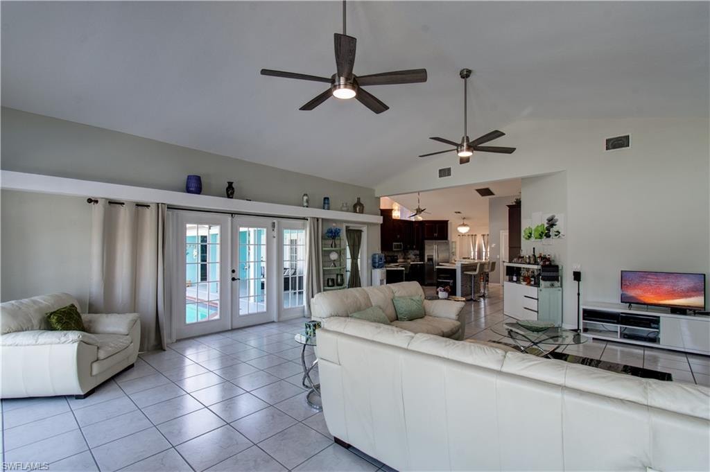Living area with french doors, light tile patterned floors, a ceiling fan, and high vaulted ceiling