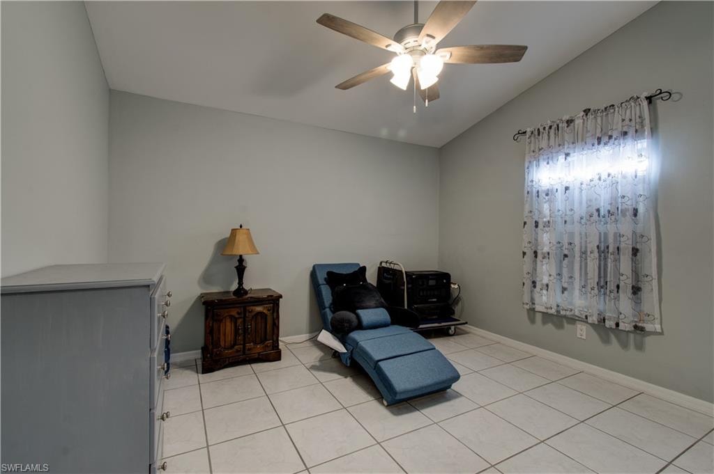 Sitting room with lofted ceiling, light tile patterned floors, and a ceiling fan