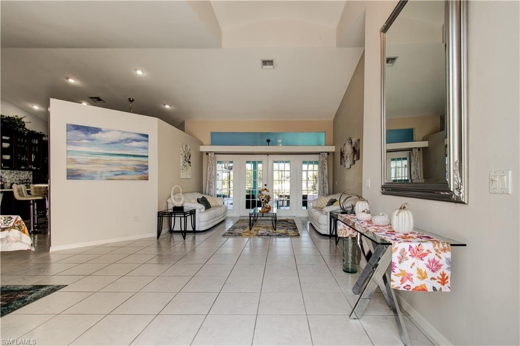 Living area featuring vaulted ceiling, french doors, light tile patterned flooring, and recessed lighting