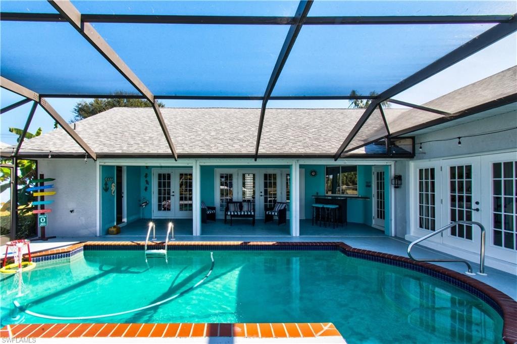 Outdoor pool featuring french doors, a sunroom, glass enclosure, and a patio