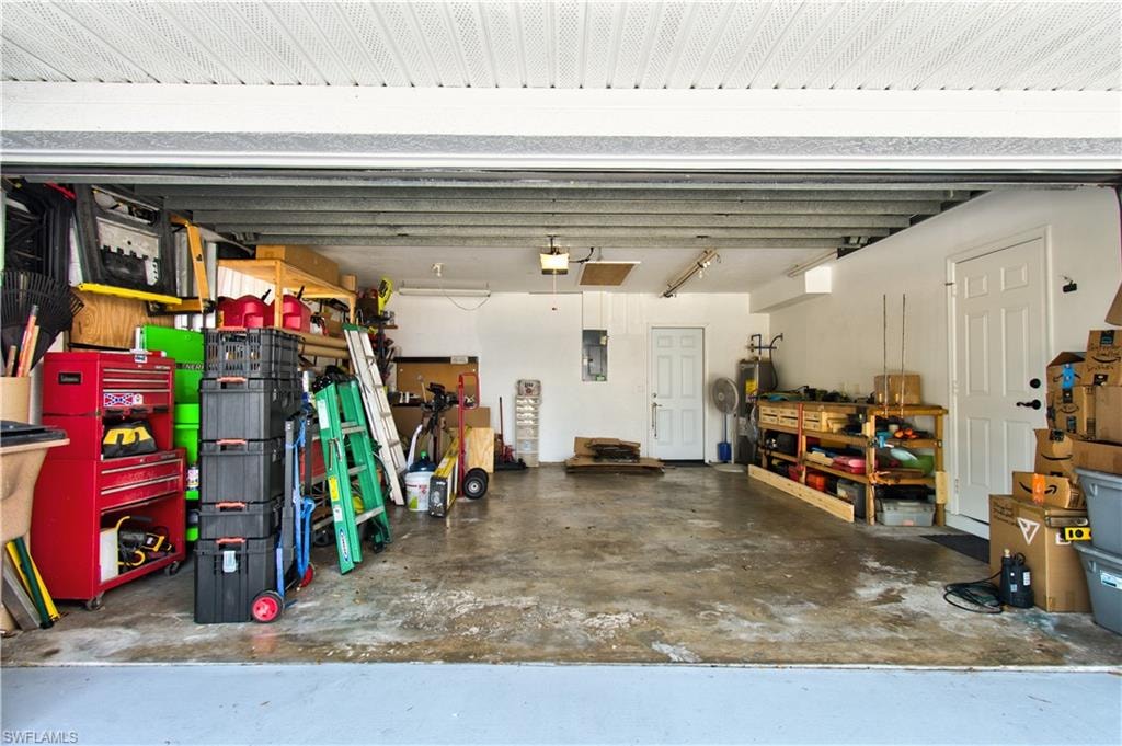 Garage featuring a workshop area, electric panel, and electric water heater