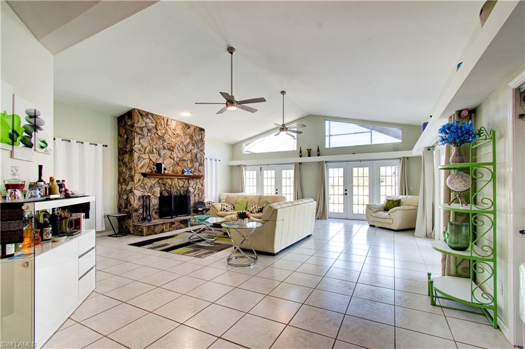 Living room featuring french doors, light tile patterned floors, a fireplace, high vaulted ceiling, and ceiling fan