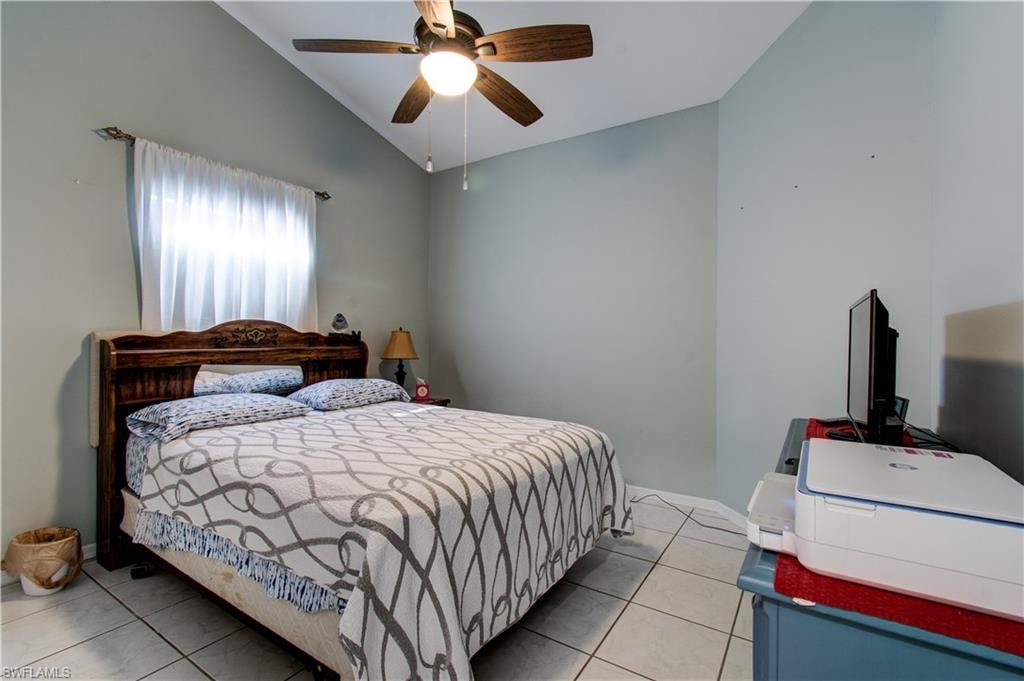 Bedroom with vaulted ceiling, a ceiling fan, and light tile patterned floors
