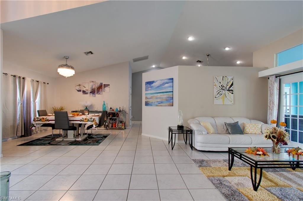 Living area with lofted ceiling, light tile patterned flooring, and recessed lighting