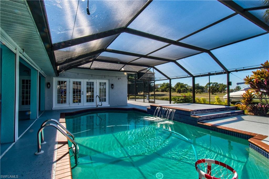 View of swimming pool with a lanai, a patio, a sunroom, french doors, and a pool with connected hot tub
