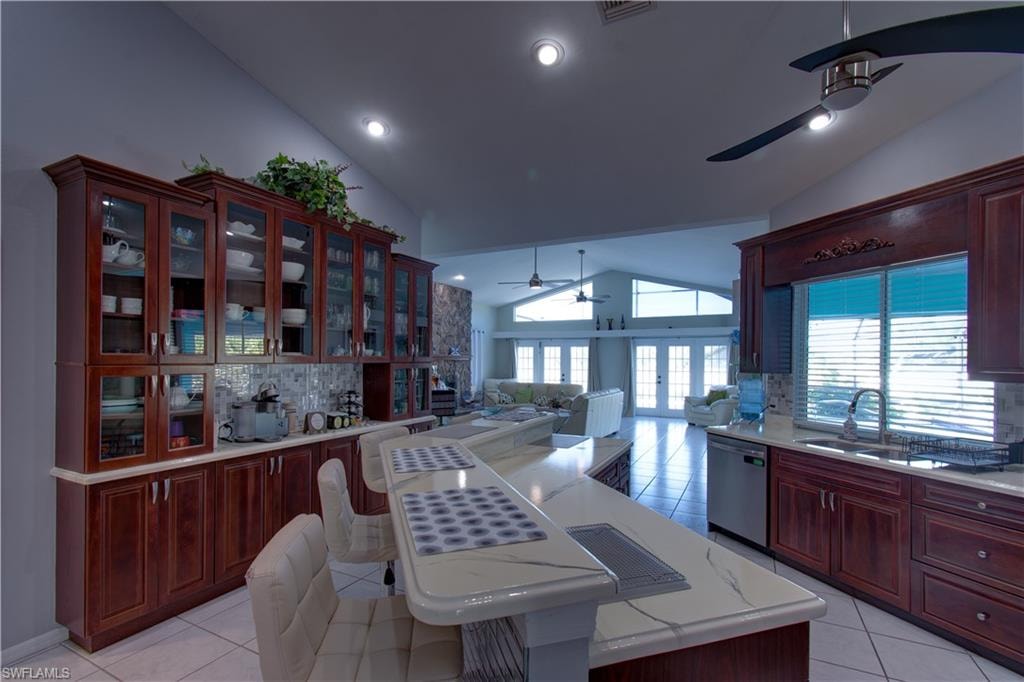 Kitchen featuring backsplash, open floor plan, a ceiling fan, light tile patterned floors, and high vaulted ceiling