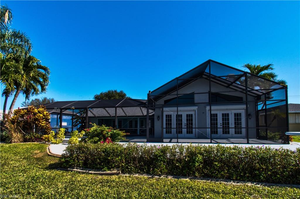 Rear view of property featuring a lanai, a sunroom, and an outdoor pool