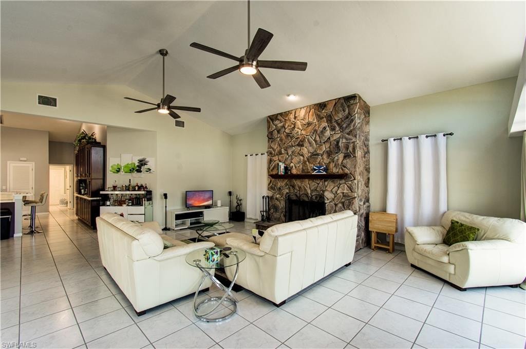 Living room with light tile patterned flooring, a fireplace, a ceiling fan, and high vaulted ceiling
