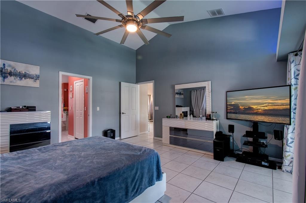 Bedroom with light tile patterned floors, high vaulted ceiling, and ceiling fan