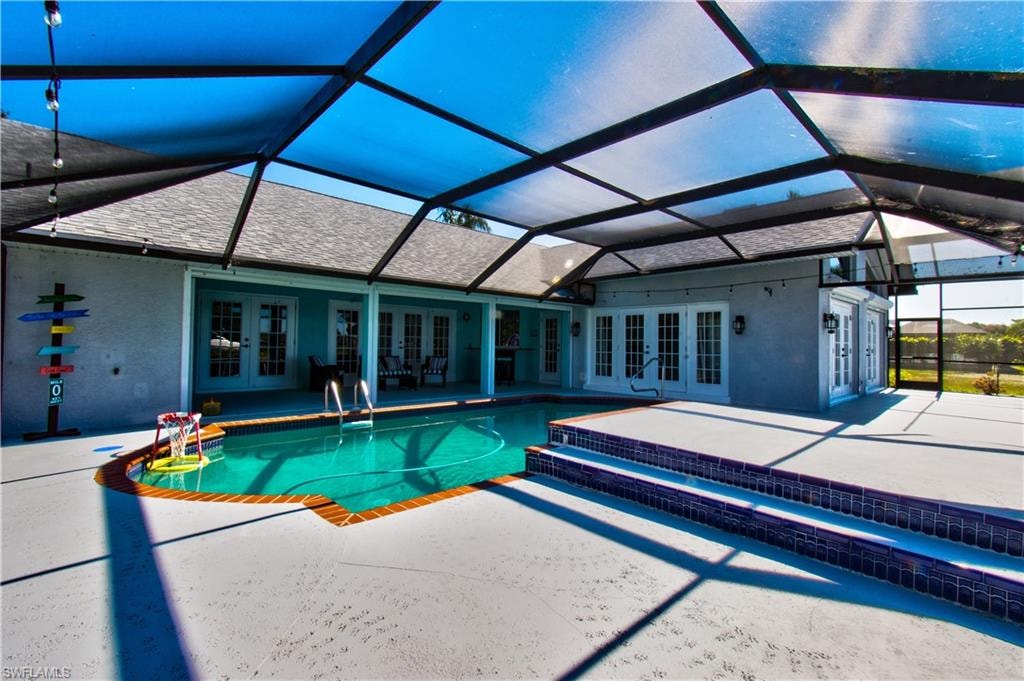 Swimming pool featuring french doors, a sunroom, and a lanai