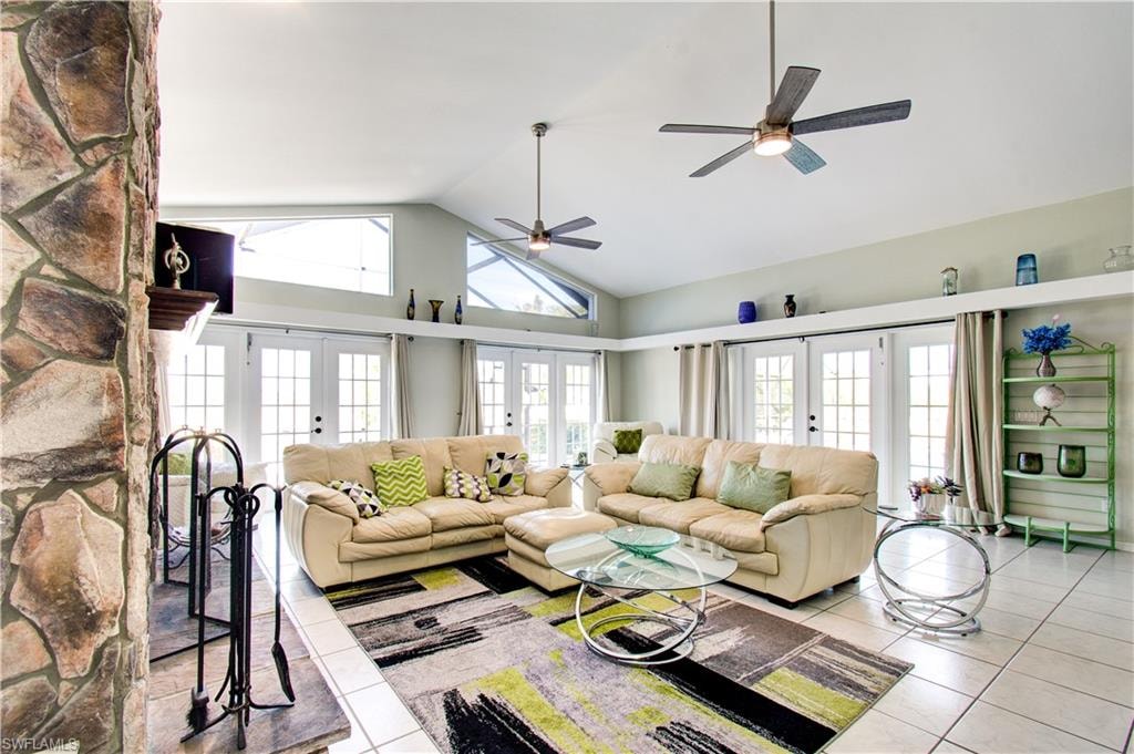 Living room with french doors, tile patterned flooring, high vaulted ceiling, and ceiling fan