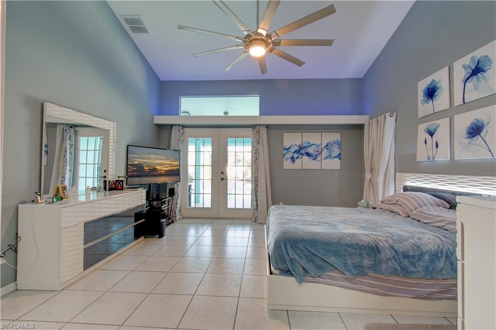Bedroom with access to exterior, french doors, a high ceiling, a ceiling fan, and light tile patterned floors