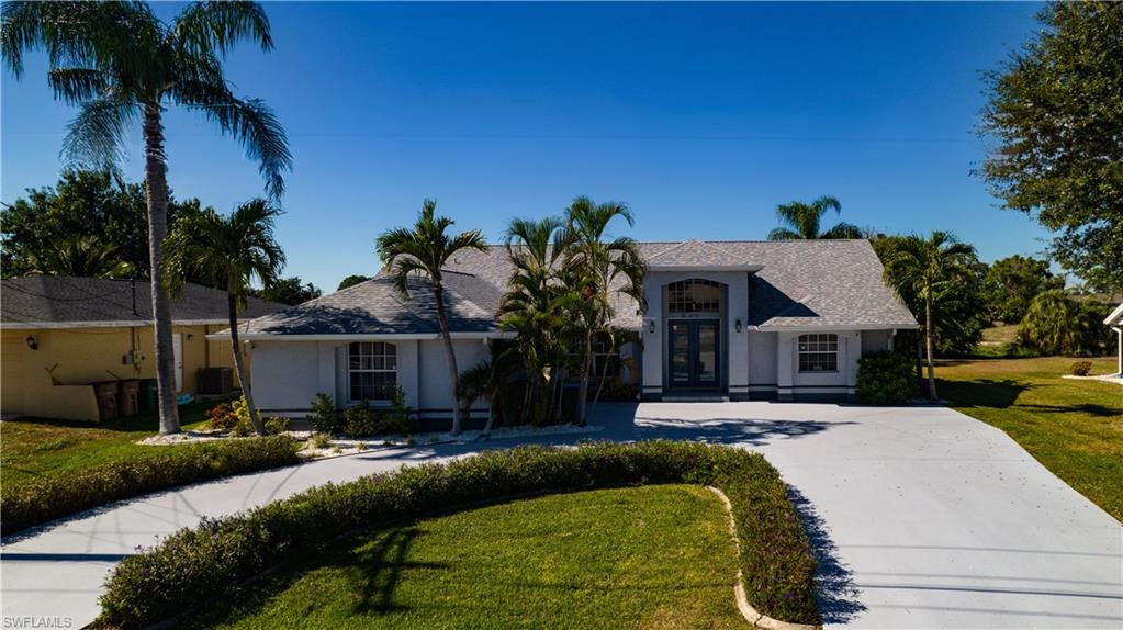 View of front facade featuring french doors, a front lawn, stucco siding, and curved driveway