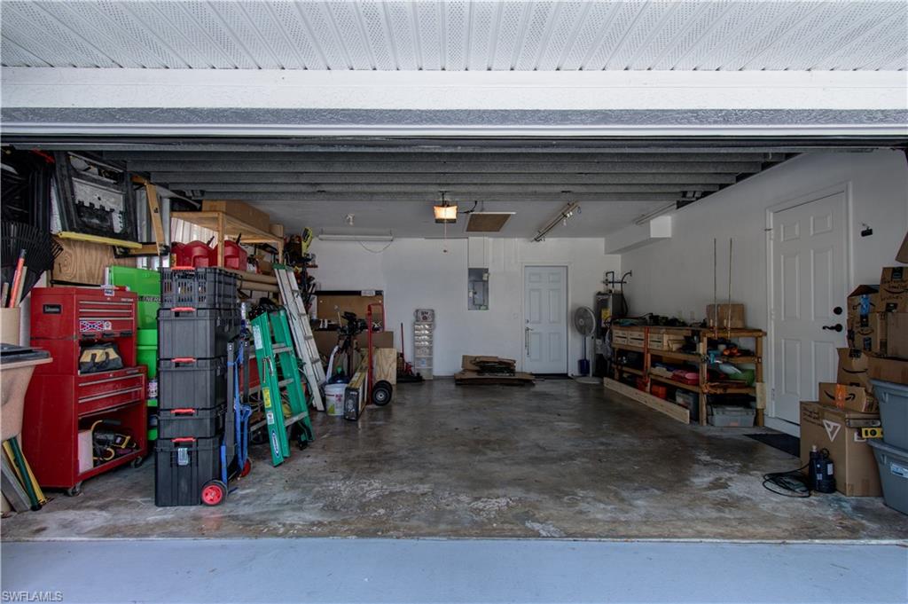 Garage featuring electric panel, a workshop area, and electric water heater
